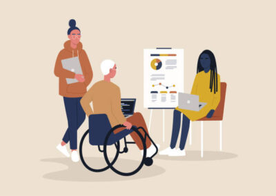 trzech ludzi jeden siedzi na wózku inwalidzkim trzymając laptop pozostałe dwie osoby przedstawiają różne wykresy